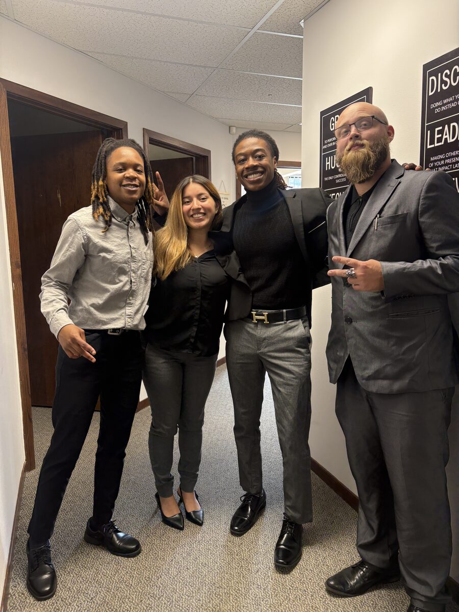 Four Intuitive Career Solutions team members in business attire in the Saginaw office, beside the company values wall
